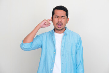 Adult Asian man showing pain expression when putting finger inside his ear