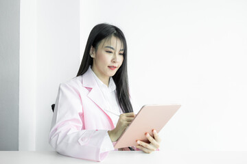 Asian woman doctor using digital tablet gadget technology on white background, Asian woman doctor in pink coat with digital tablet, Medical and healthcare working diagnosing examination health.