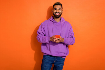 Photo of nice positive guy blogger wear stylish outfit use gadget make post for instagram followers isolated on orange color background