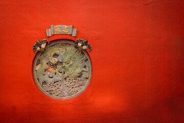Red color wall with traditional totem sculpture of dragon - obrazy, fototapety, plakaty