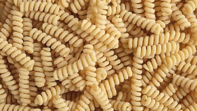 Gluten Free Cornmeal Pasta Wallpaper. Spiral Raw Macaroni from Blend of Corn and Rice flour rotating on Turntable. Close Up Top View. Uncooked Rotini Pasta is Spinning. Full Frame. Food Background. Ad