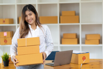 Fototapeta na wymiar Portrait of Asian young woman SME working with a box at home the workplace.start-up small business owner, small business entrepreneur SME or freelance business online and delivery concept.