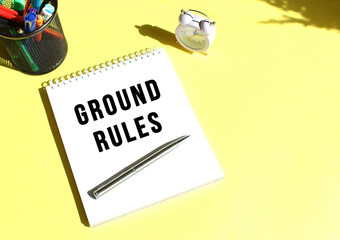 Notepad with text GROUND RULES with stationery. Yellow background color.