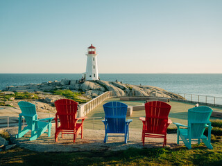 Colorful Adirondack chairs and Peggys Cove Lighthouse, Peggys Cove, Nova Scotia, Canada