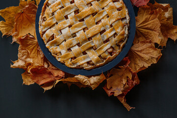 Traditional  English (American) apple pie with braided crust on background of fallen autumn leaves...