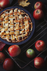 English (American) apple pie with braided crust; fresh apples and fallen leaves around it on...