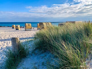View of the sandy beach, traditional north german beach chairs and beach grass on the island Fehmarn on Baltic sea - obrazy, fototapety, plakaty