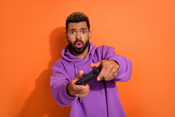 Photo of funny excited dude boy man have fun chill use playstation isolated on vivid orange color background © deagreez