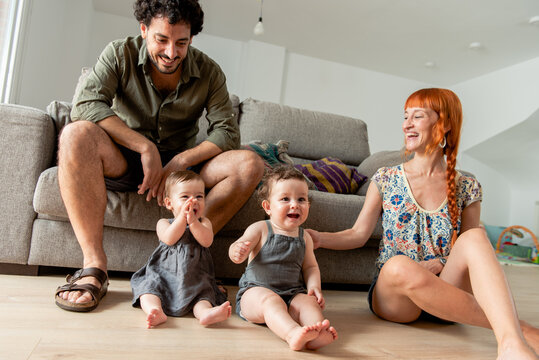 Cheerful diverse family with adorable little twins sitting on floor at home