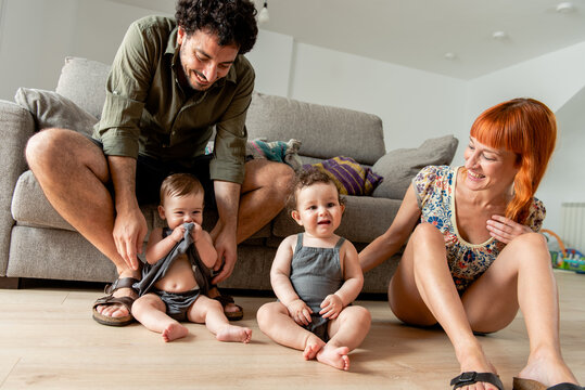 Cheerful diverse family with adorable little twins sitting on floor at home
