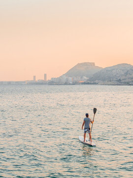 Man With Paddle On Surfboard On High Seas