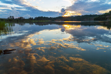 A mirror image in the aquatic environment at sunset with clouds.