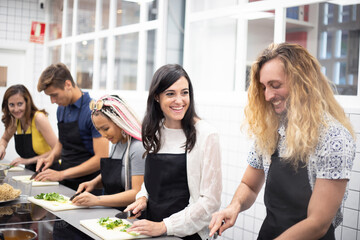 Multiracial people learning how to cut vegetables at cooking workshop