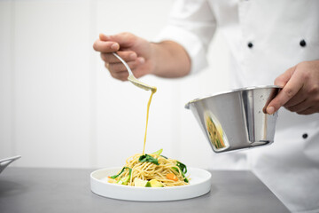 Professional chef demonstrating process of serving dish on plate at cooking workshop