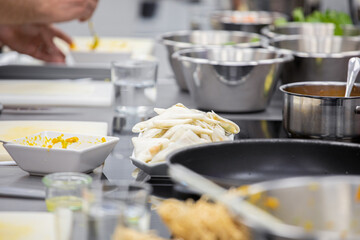 Kitchen table with stainless pots and cooked Asian dish at cooking workshop