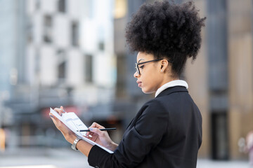 Serious female architect with draft of building in city
