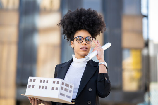 Black female architect with model of building in city
