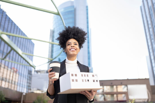 Black female architect with model of building in city - Powered by Adobe