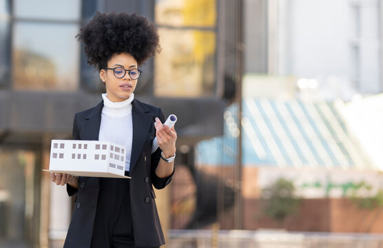 Black female architect with model of building in city