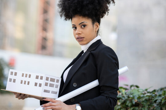 Black female architect with model of building in city