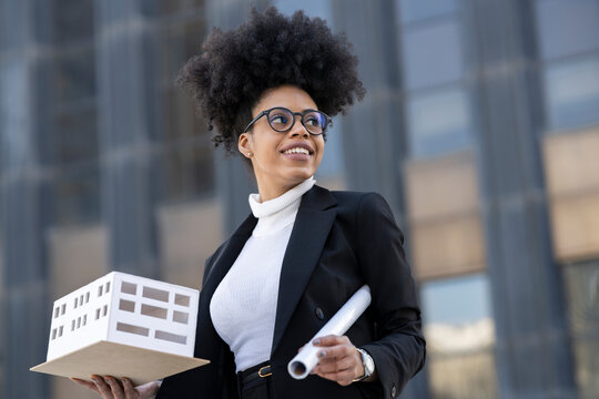 Black female architect with model of building in city - Powered by Adobe
