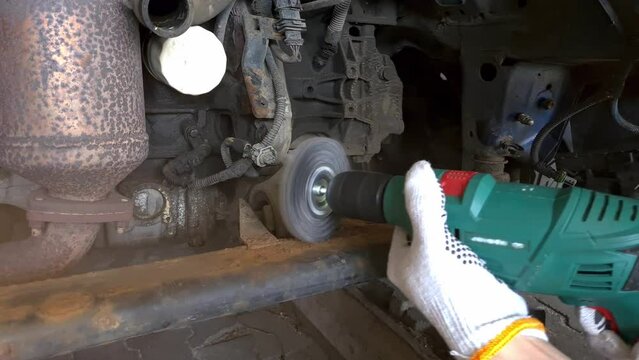 Old car undercarriage maintenance, engine compartment sled cleaning with a drill with a wire brush