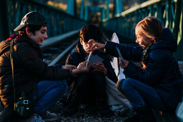Group of three children playing cards in a train track