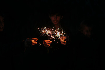 Group of young friends with sparkles on forest