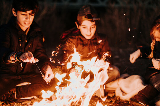 Group Of Young Friends Camping And Burning A Wood Fire