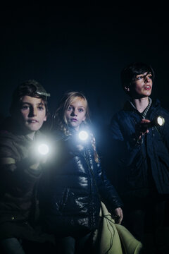 Children camping and playing with torch lantern in the dark