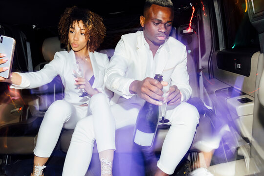 African American couple taking selfie in limousine
