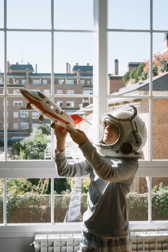 Adorable kid with helmet playing with a toy plane