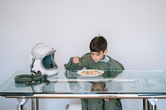 Boy dressed in an astronaut costume sitting at the table eating