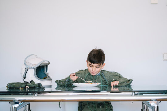 Boy dressed in an astronaut costume sitting at the table eating