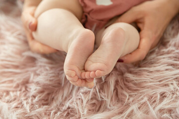 Baby's foot in mother hands closeup on pink fluffy rug , New family and baby healthy concept.