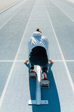 Anonymous athlete in crouch start position on starting blocks
