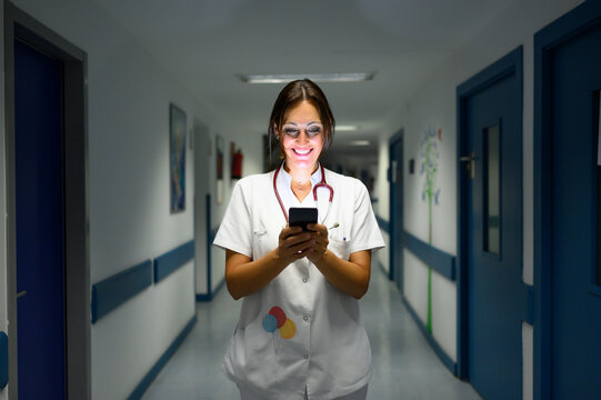 Cheerful Pediatrician Using Smartphone In Hospital Hallway