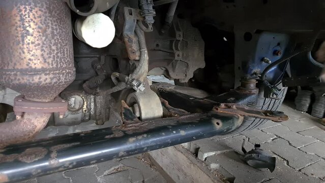 Maintenance of the chassis of an old car, cleaning of a corroded sledge in the engine compartment with a wire brush
