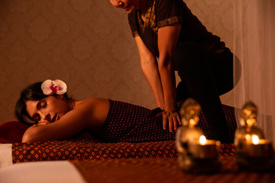 Thai female massagist giving a massage to a young woman