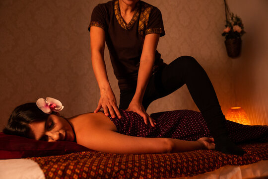 Thai female massagist giving a massage to a young woman