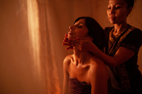 Thai female massagist giving a massage to a young woman