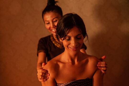 Thai female massagist giving a massage to a young woman