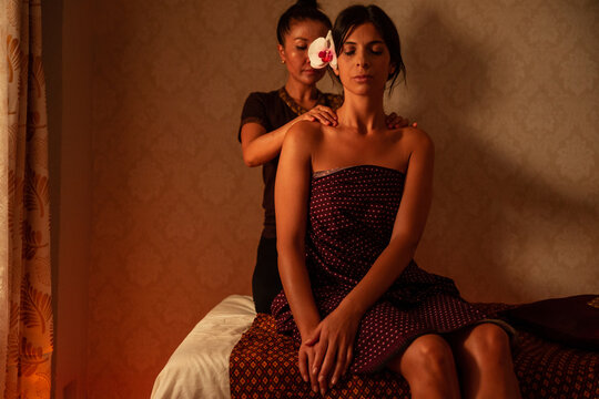 Thai female massagist giving a massage to a young woman