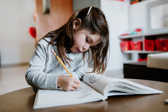 Concentrated Girl Drawing In Coloring Book