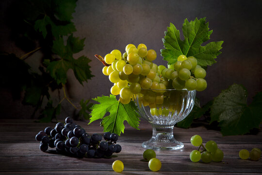 Still life with a bunch of green, red grapes and grape leaves
