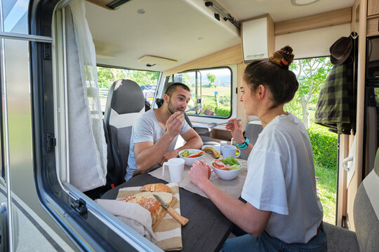 Traveling couple eating lunch in caravan