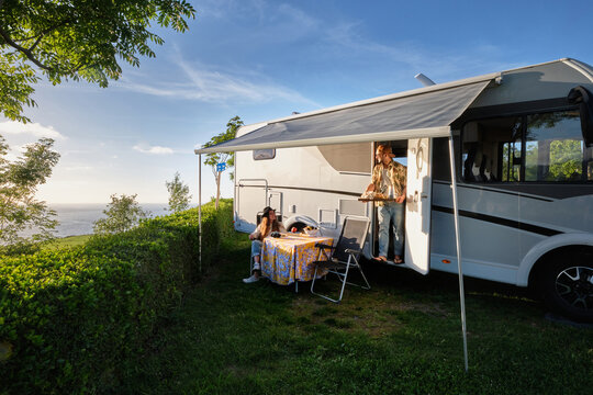 Traveling couple having dinner at table near camper