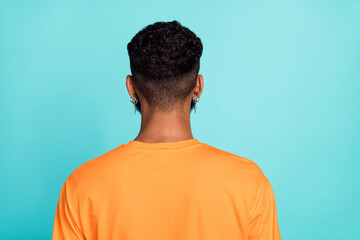 Photo of attractive handsome man dressed orange t-shirt standing back showing new haircut isolated turquoise color background