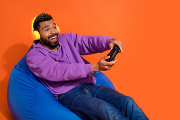 Portrait of excited carefree person addicted playing video games isolated on orange color background