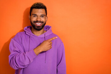 Portrait of cheerful nice person indicate finger empty space promotion isolated on orange color background